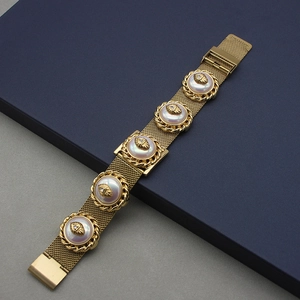 Macro shot of gold mesh bracelet with inlaid round imitation pearls on blue box