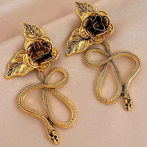 Close-up of vintage gold snake earrings featuring intricate rose flower studs