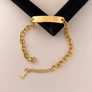 Macro shot of polished gold stainless steel chain bracelet with crystal curved bar and lobster clasp
