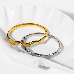 Minimalist Mobius loop cuff bracelets in gold and silver finish on a shell tray