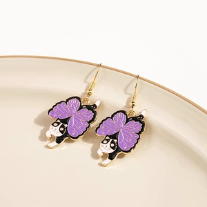 Close-up of cat earrings with purple butterfly wings on a ceramic plate detail