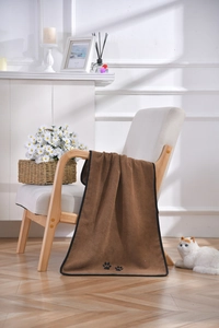 Detail of thick brown microfiber pet towel with paw embroidery on a wooden chair