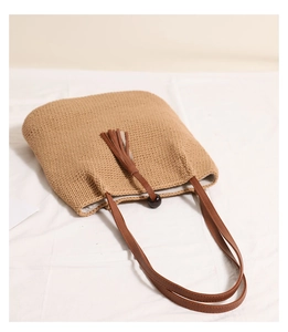 Detail of woven beach bag with wooden bead tassels and premium leather shoulder straps