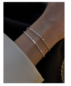 Close-up of layered silver bracelet featuring a shimmering bead chain and a sparkling rhinestone band