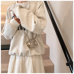 Detail view of a silver fish-shaped mini crossbody bag with a metallic chain on a model