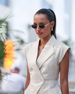 Close-up of sleeveless V-neck lapel top in cream white with a slim waist detail