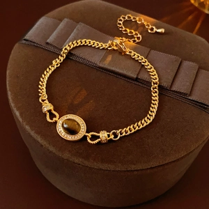 Detail of gold-plated bracelet with oval tiger eye stone and cubic zirconia on a gift box