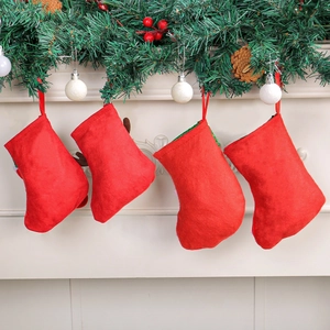 Vier rote Weihnachtssocken hängen an einem festlichen Kaminsims mit Kieferndekoration
