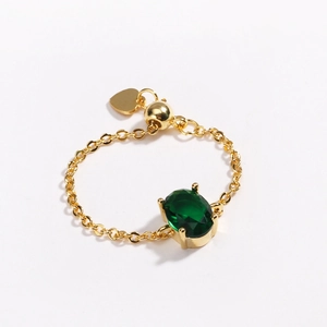 Detail of adjustable gold-plated chain ring featuring a green oval zircon and heart charm