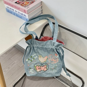 Detail of red and white checkered lining inside a blue denim tote bag with floral embroidery