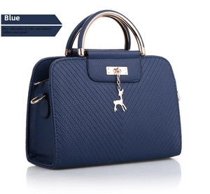 Detail of dark blue lychee grain leather handbag with stitching and gold deer charm