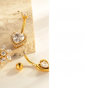 Macro shot of gold heart belly ring with clear cubic zirconia and screw-on detail