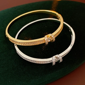Macro shot of gold and silver buckle bangles with sparkling pavé zircons on green velvet