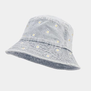 Detail of light blue denim bucket hat with delicate white daisy embroidery texture