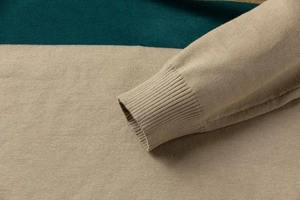 Detailed close-up of ribbed cuffs and two-tone knit fabric in beige and dark green