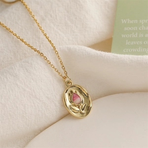 Détail macro du pendentif ovale doré avec tulipe en émail rose et gravure vintage