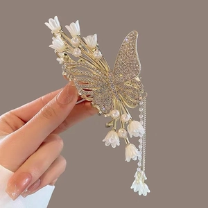 Detail of gold butterfly hair claw with white lily of the valley and pearl tassels