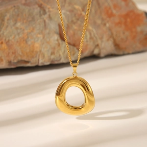 Detail shot of a golden irregular ring pendant on a stainless steel necklace chain