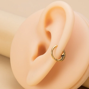 Close-up of gold moon-embossed hoop ring on an ear model showing intricate textures