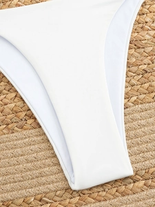 Detailed close-up of premium white bikini fabric texture on a woven beach mat