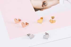 Detailed view of heart-shaped stud earrings in rose gold, gold, and silver finishes