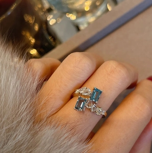 Luxuriöser offener Ring mit blauen Edelsteinen und Zirkonia an der Hand getragen