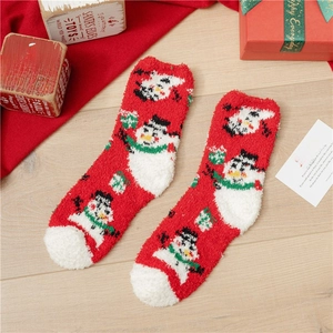 Detail of red Christmas coral fleece socks with snowman pattern in festive gift setting