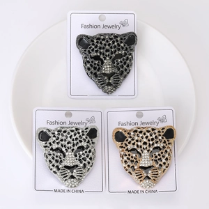 Macro di tre spille a testa di leopardo in oro, argento e nero con strass lucidi