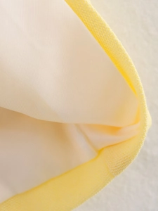 Macro shot of yellow linen-textured fabric with soft cream-white lining and edge detail