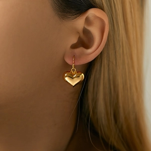 Close-up of heart-shaped gold earrings worn by model showcasing polished metallic shine