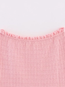 Macro detail of pink knit fabric showing delicate ruffle texture and intricate stitching