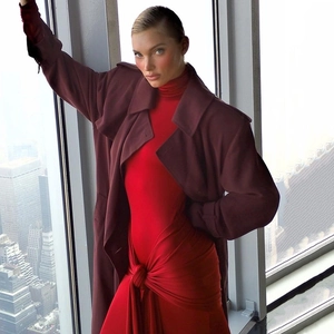 Détail d'une robe longue rouge à col montant avec nœud et trench-coat rouge foncé
