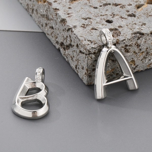 Silver A and B initial pendants with sparkling zircon stones on a grey stone background