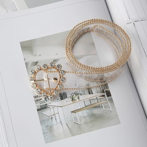 Detail of transparent PVC belt featuring gold beaded edges and a rhinestone heart buckle