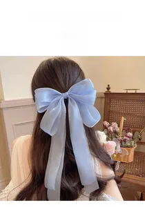Detail of light blue organza ribbon bow hair clip showing sheer texture and elegant draping
