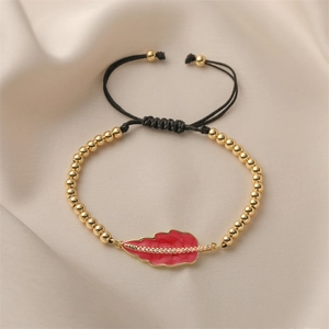 Adjustable woven bracelet featuring gold beads and a red enamel leaf pendant with zircons