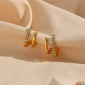 Macro detail of gold-plated double-layer U-shaped earrings with cubic zirconia on satin