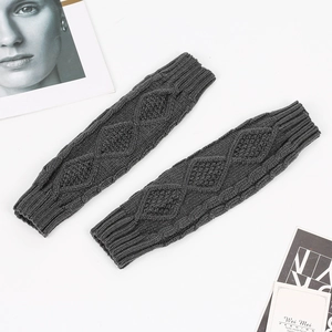 Macro detail of dark grey knit arm warmers featuring classic diamond cable patterns