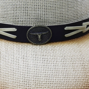 Macro view of woven straw hat featuring a leather band and vintage longhorn bull emblem