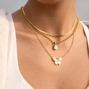 Détail du collier triple rang doré avec pendentifs papillon et zircon en goutte