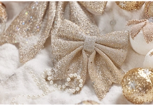 Close-up of champagne gold glitter bow with pearl string on white plush Christmas decor