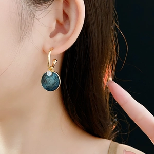 Close-up of vintage flower earrings with blue geometric charms and zircon on model