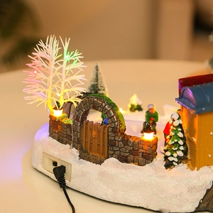 Close-up of LED glowing Christmas miniature house with snowy resin pine trees and snowman