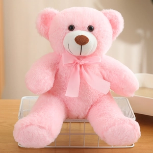 Pink plush teddy bear with a silk ribbon sitting on a white metal shelf in a cozy room