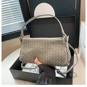 Dettaglio ravvicinato della pelle grigia intrecciata e hardware dorato della borsa a tracolla