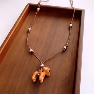 Collier artisanal avec pendentif chien en émail orange et perles argentées