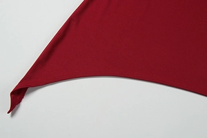 Close-up of dark red knit dress hem with asymmetric point and double stitching detail