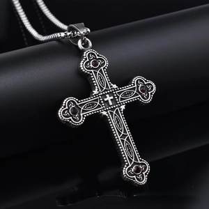 Macro detail of Gothic cross pendant with red stones and vintage silver engraving