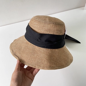 Dettaglio del cappello da sole in lino kaki con trama intrecciata e fiocco nero in nastro