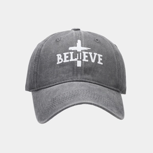 Close-up of white BELIEVE text and cross embroidery on vintage dark grey baseball cap